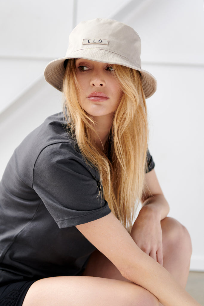 Womens athleisure wear. Model wearing vintage black tee with beige bucket hat.