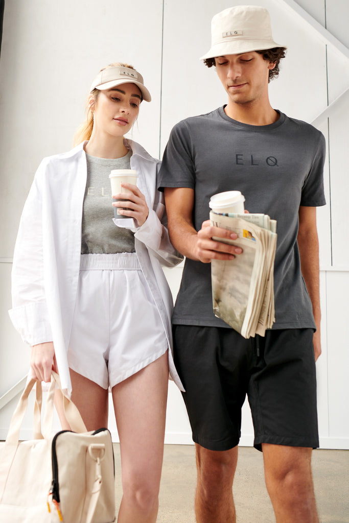 Unisex athleisure, womens and mens streetwear. Grey and black tee, beige crossbody sports bag, beige bucket hat and beige visor hat